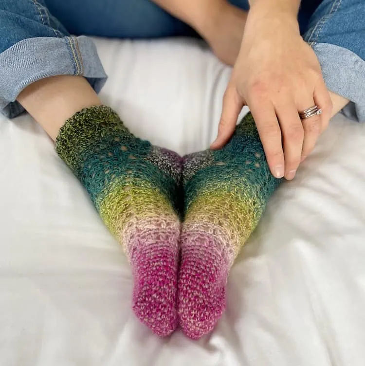 calcetines de ganchillo lacy ombre que se usan con los pies juntos y la mano sosteniendo el tobillo