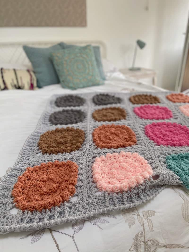 colourful and modern crochet blanket laying on a bed