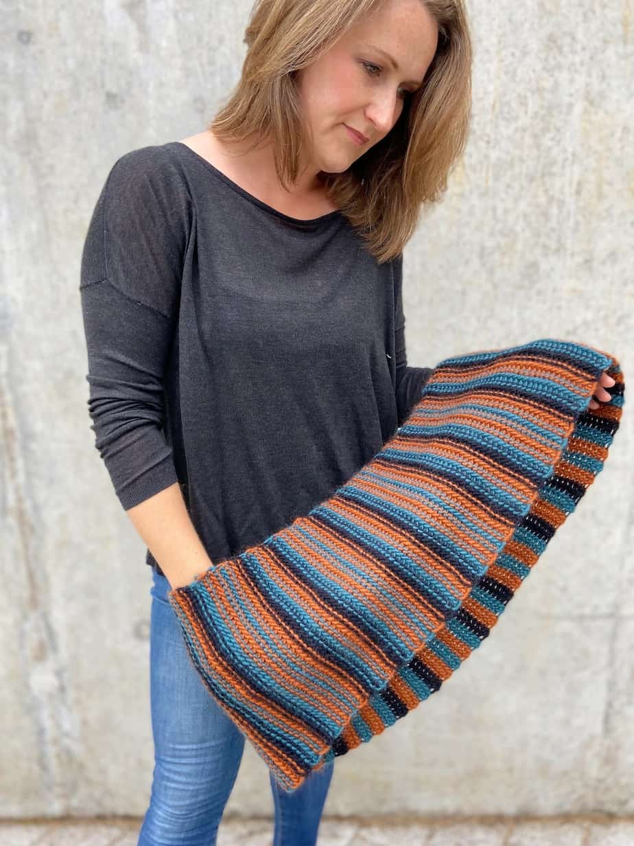 person in jeans and jumper holding chunky crochet cowl across hands