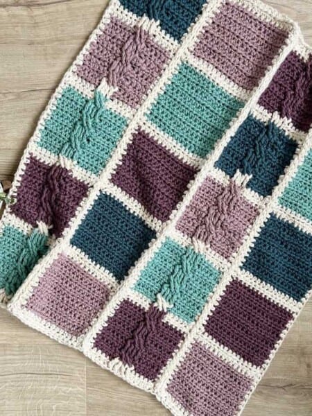 Patchwork Crochet Blanket Pattern laid on floor next to houseplant