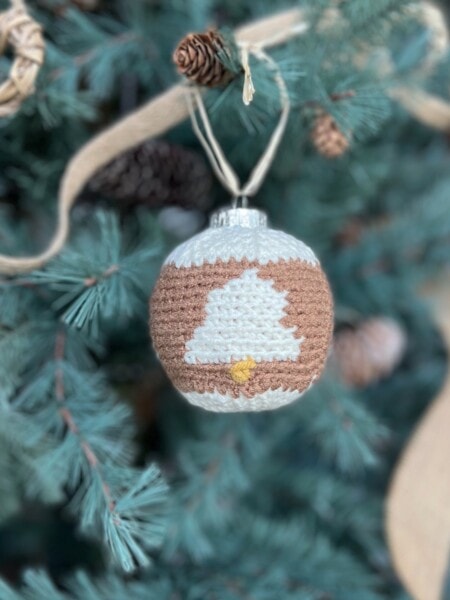 Crochet bauble pattern with bells on hanging on a tree.