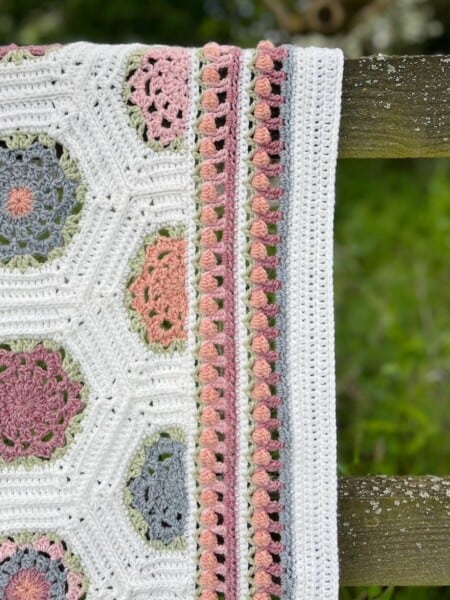 Crochet flower border in pastel colours on a blanket.