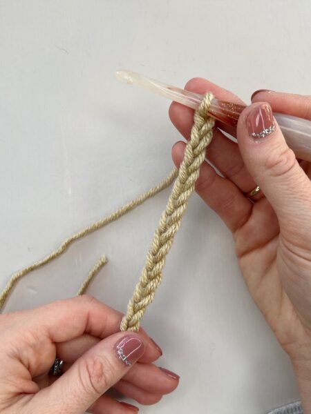 A person using a crochet hook to make a chain stitch.