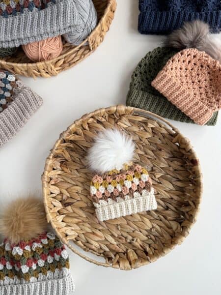 Crocheted hats in baskets with pom poms.