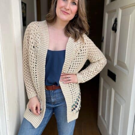 A woman in a beige cardigan and blue top standing in a doorway.