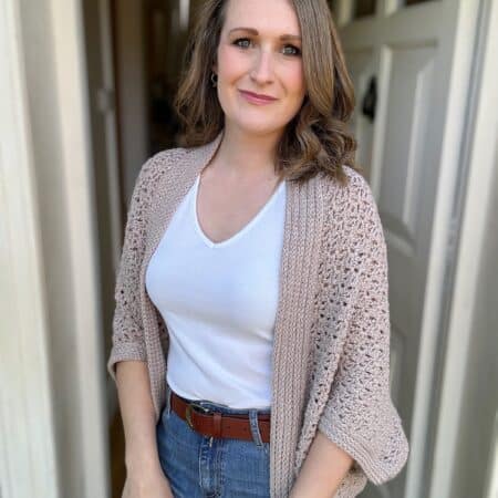 Woman wearing a relaxed cocoon crochet cardigan in a neutral colour.