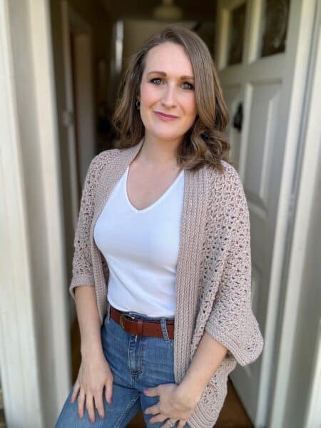 Woman wearing a relaxed cocoon crochet cardigan in a neutral colour.