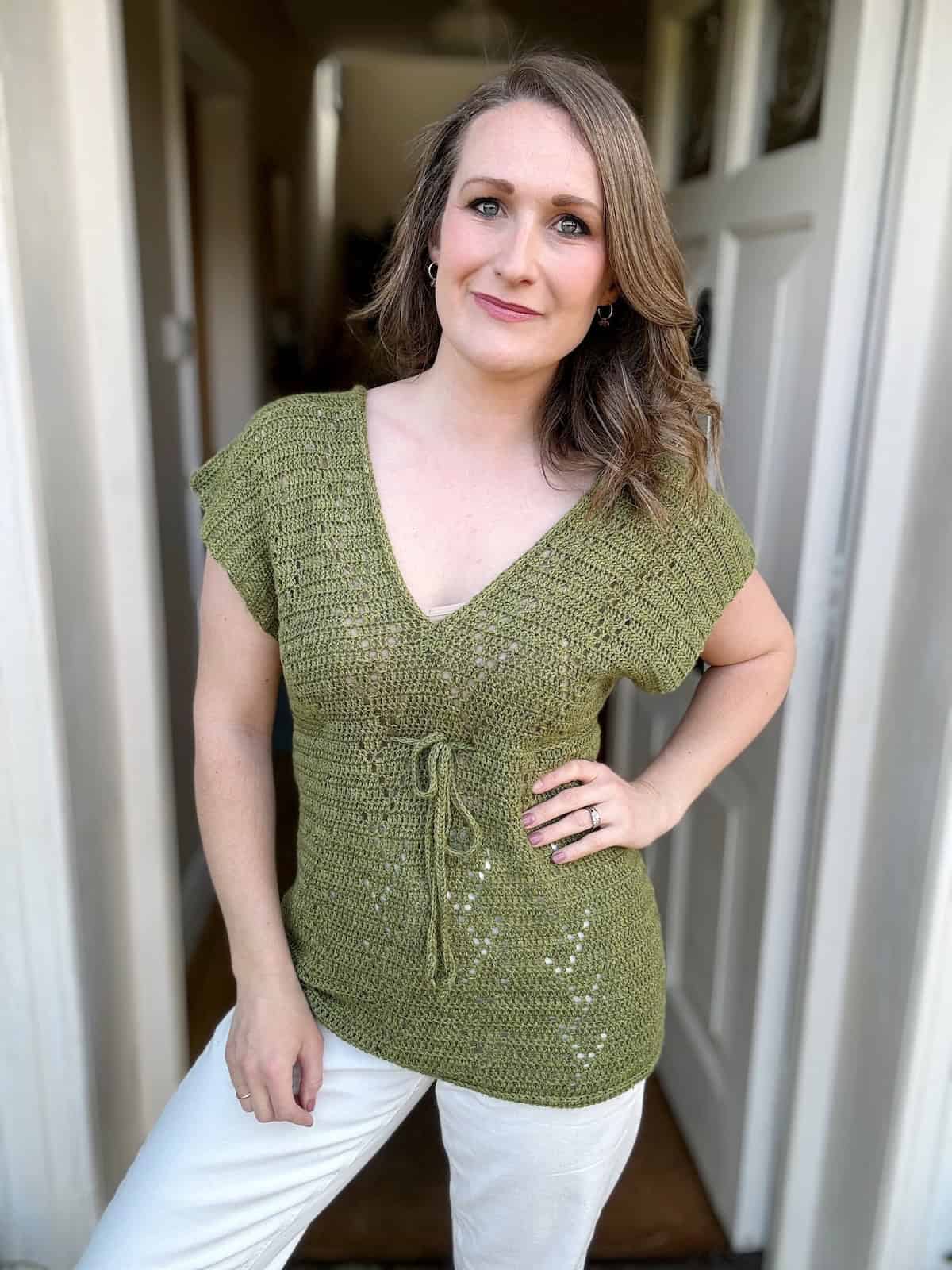 Woman wearing green summer crochet top with hand on hip.