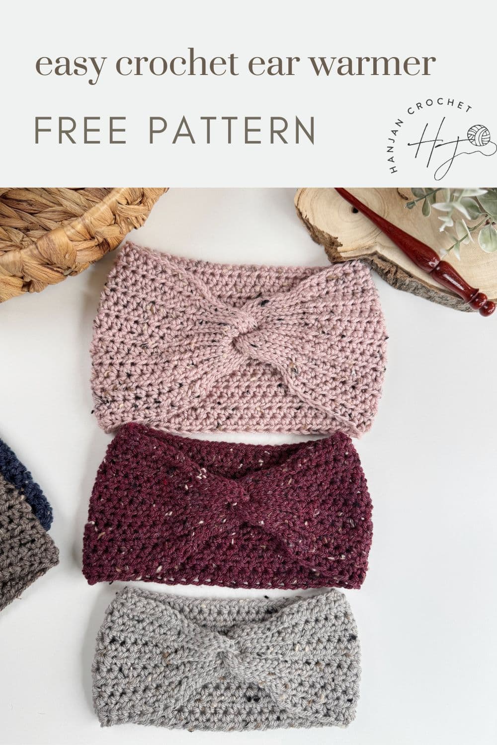 Three crocheted ear warmers in pink, red, and gray are displayed on a white surface next to a crochet hook and a woven basket. The text above enticingly offers an "easy crochet ear warmer pattern" for free.